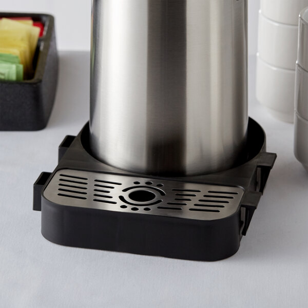A stainless steel Acopa airpot rack with drip tray holding a silver airpot.