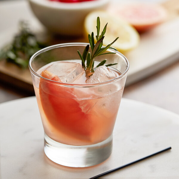A Libbey rocks glass with a drink, ice, and a sprig of rosemary.