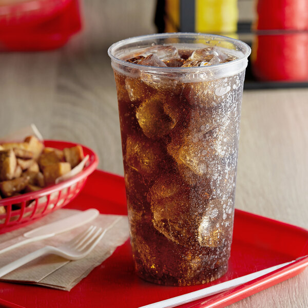A Fabri-Kal Greenware plastic cup filled with ice and soda on a red tray.