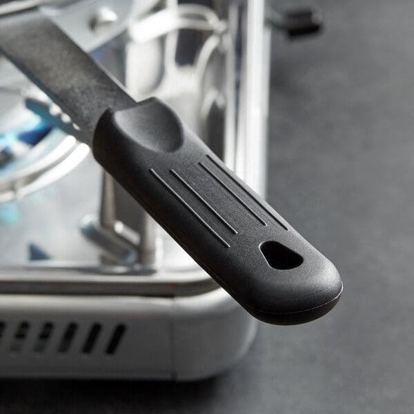A black removable silicone pan handle on a metal object.