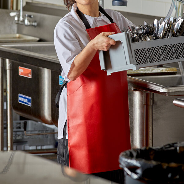 A woman adjusting a red Intedge vinyl apron in a kitchen.