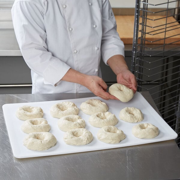 A chef using a Winholt plastic proofing board to prepare doughnuts.