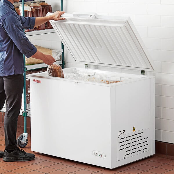 A man putting a bag of bread into a Galaxy commercial chest freezer.