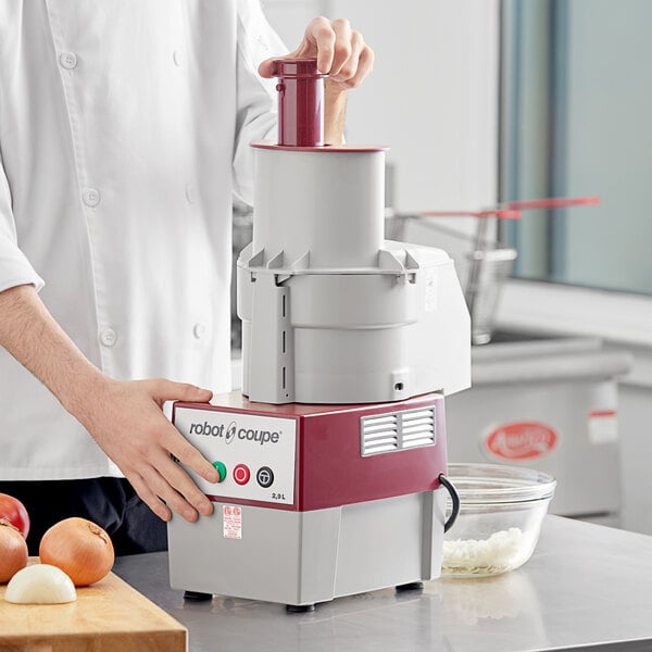 A chef using a Robot Coupe food processor to dice onions.