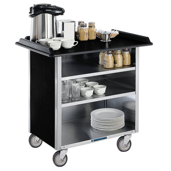 A Lakeside stainless steel beverage service cart with black vinyl shelves holding dishes and cups.