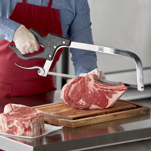 A person using a Backyard Pro Butcher Hand Meat Saw to cut meat on a counter.