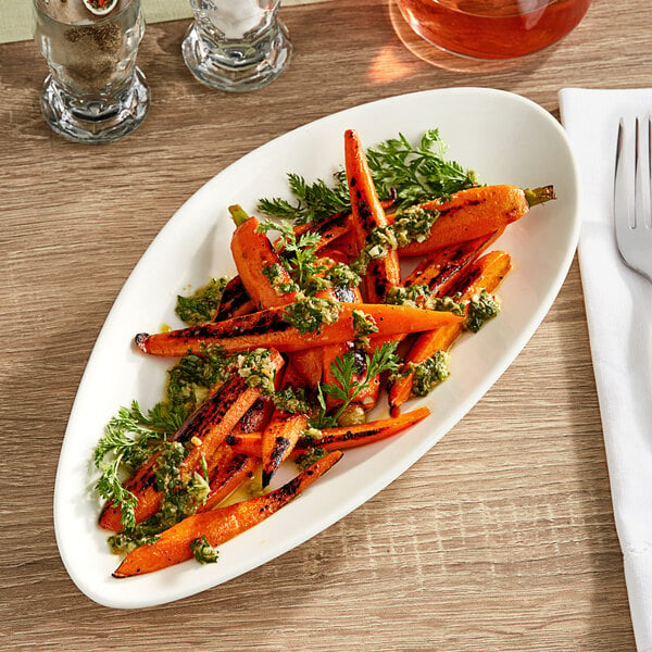 A Acopa Nova cream white stoneware plate with food including carrots and parsley on it.