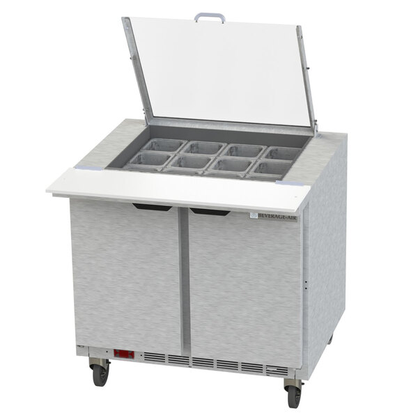 A Beverage-Air stainless steel refrigerated sandwich prep table with clear lids open over two drawers.