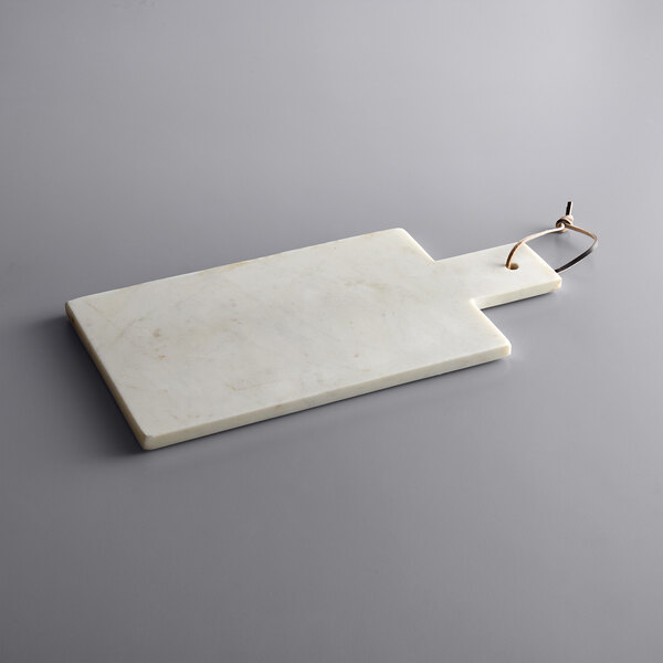 An American Atelier white marble cutting board with a metal handle.