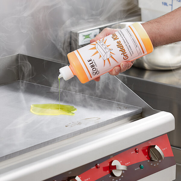 A hand pours Noble Chemical Griddle Kleen from a bottle onto a hot grill.