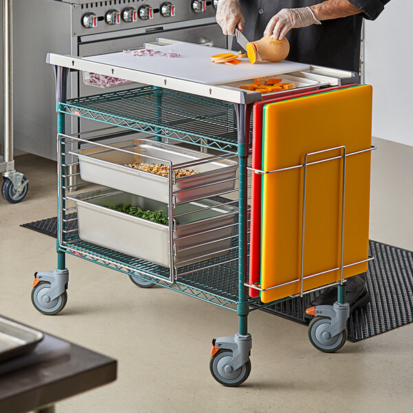 A person cutting food on a Metro PrepMate multistation cart.