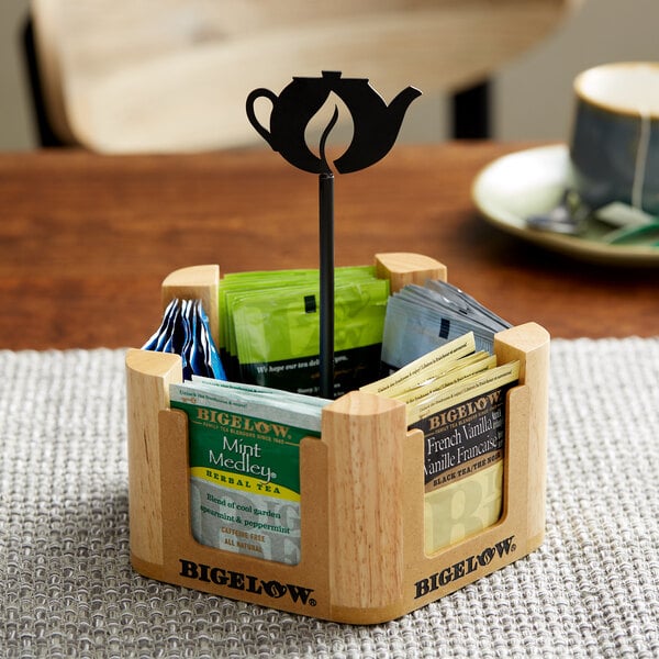 A wooden Bigelow Tea caddy with compartments holding tea bags.