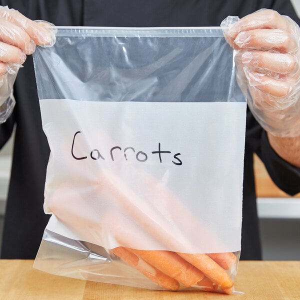 A person in gloves holding a LK Packaging plastic bag with a carrot in it.