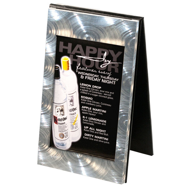A Menu Solutions aluminum and vinyl table tent with a swirl finish on a table with a menu showing pictures of vodka bottles.