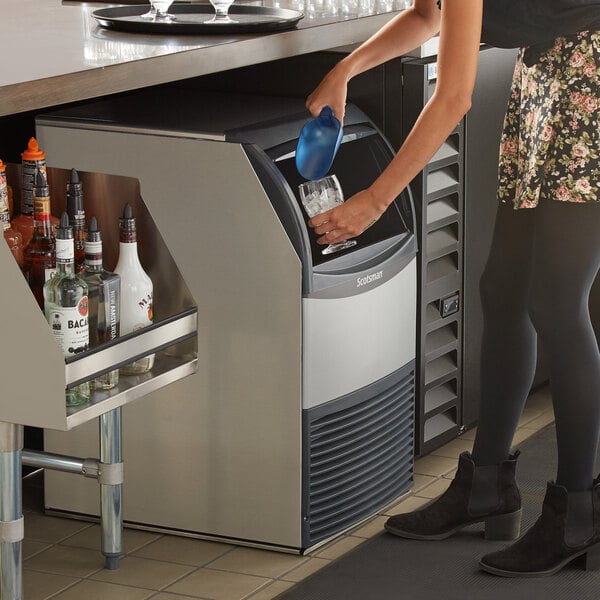 A woman pouring water into a Scotsman undercounter ice machine.