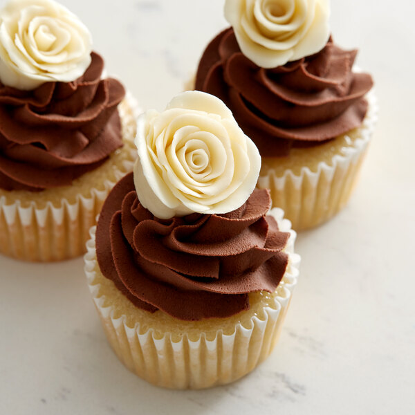 Three cupcakes with Satin Ice ivory modeling chocolate roses on top of chocolate frosting.