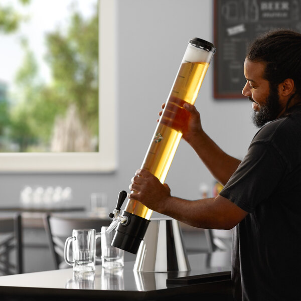 A man holding a large Beer Tubes replacement tube filled with beer and pouring it into a glass.