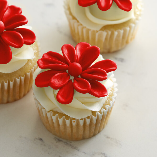 A close-up of a cupcake with Satin Ice ChocoPan red modeling chocolate on top with a red flower.