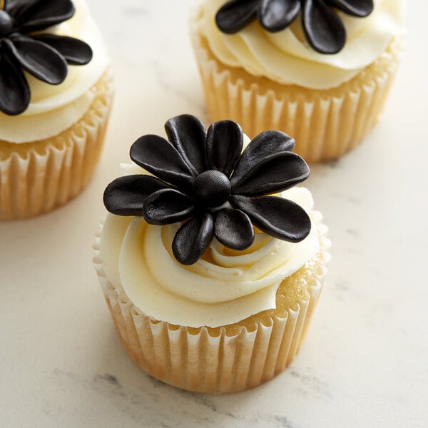 Three cupcakes with black flowers made from Satin Ice ChocoPan Modeling Chocolate on top.