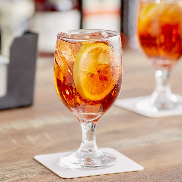 A close up of a glass of iced tea with a lemon slice in an Acopa Customizable Glass Goblet.