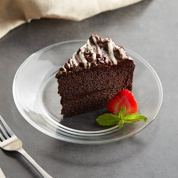 A piece of chocolate cake on a Libbey clear glass plate with a strawberry on top.