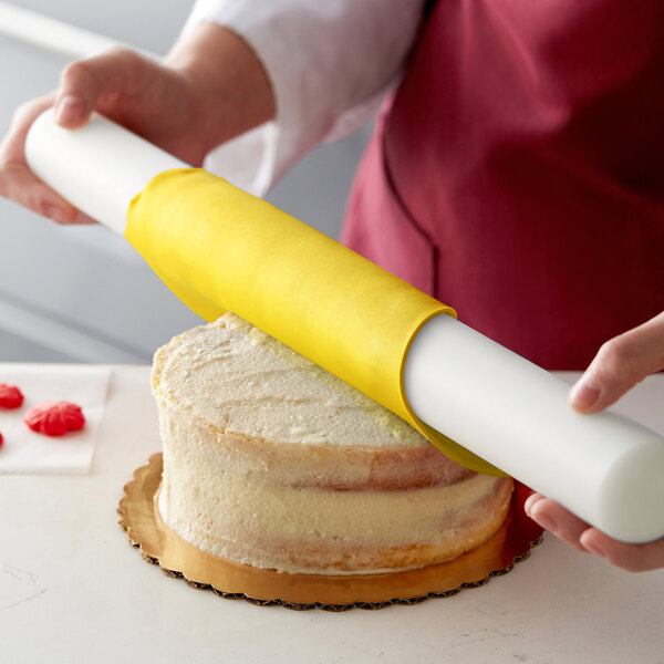 A person using Satin Ice ChocoPan yellow covering on a cake.