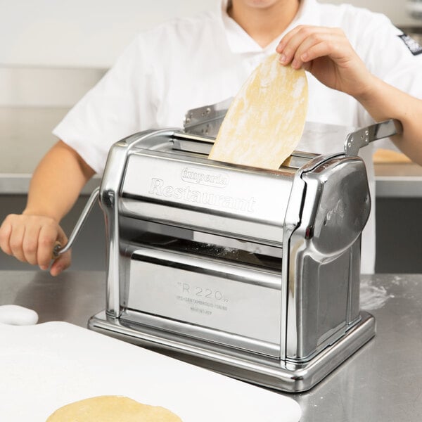 A person using an Imperia pasta machine to make dough.
