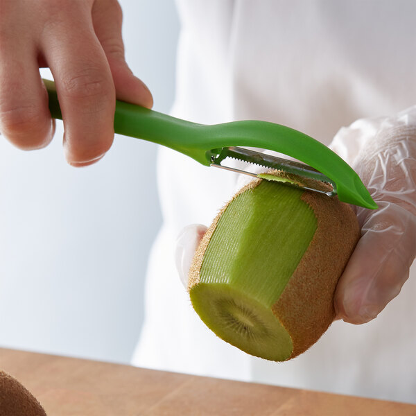A person using a Victorinox green straight vegetable peeler to peel a kiwi.