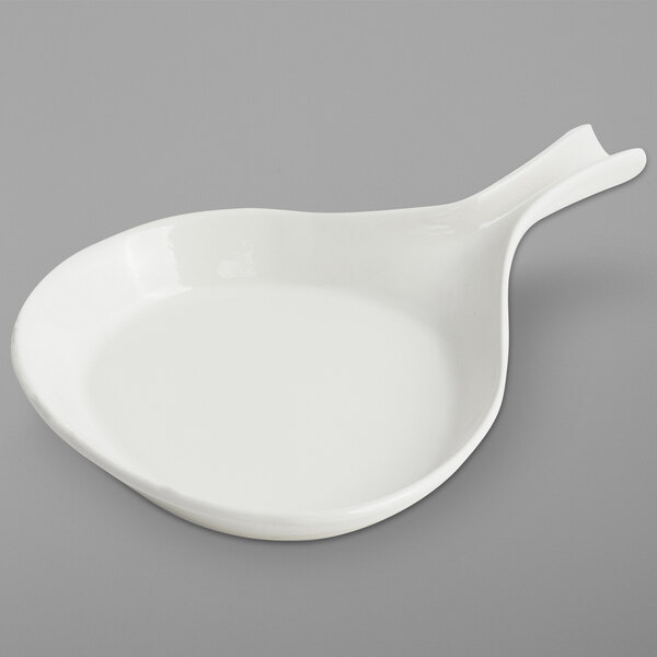 A white Bon Chef round sandstone pan with a spoon in it.