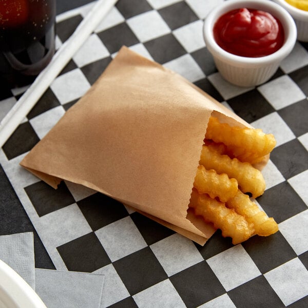 Carnival King medium kraft french fry bag filled with french fries on a checkered table.