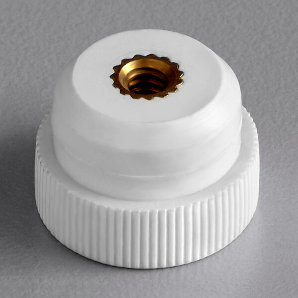 A white plastic cap with a gold nut.