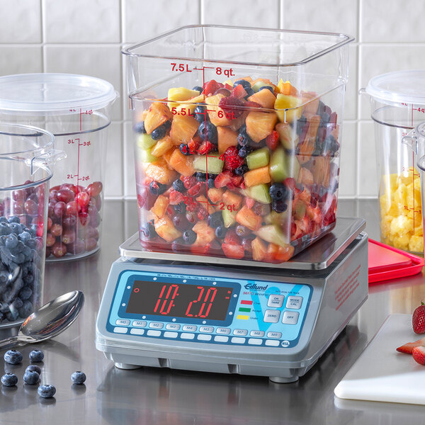 An Edlund digital portion scale with a container of fruit on it.