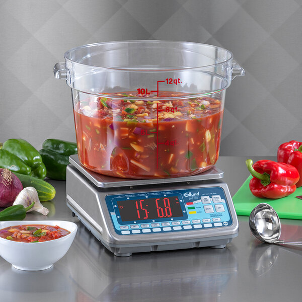 An Edlund digital portion scale with a bowl of soup and vegetables on it.