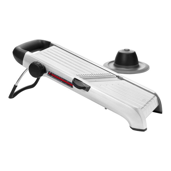 An OXO SteeL Chef's Mandoline Slicer 2.0 on a counter with a lid and a cup.