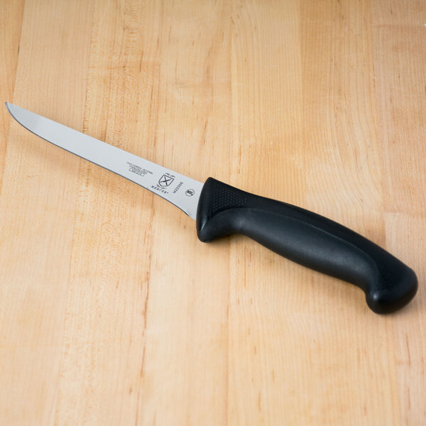 A Mercer Culinary Millennia 6" Stiff Boning Knife with a black handle on a wooden table.