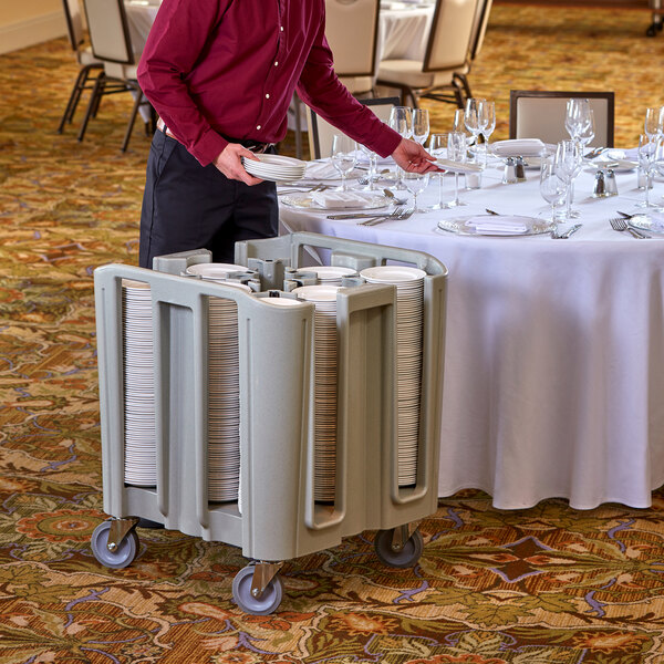 A man holding a Cambro dish dolly cart full of plates.