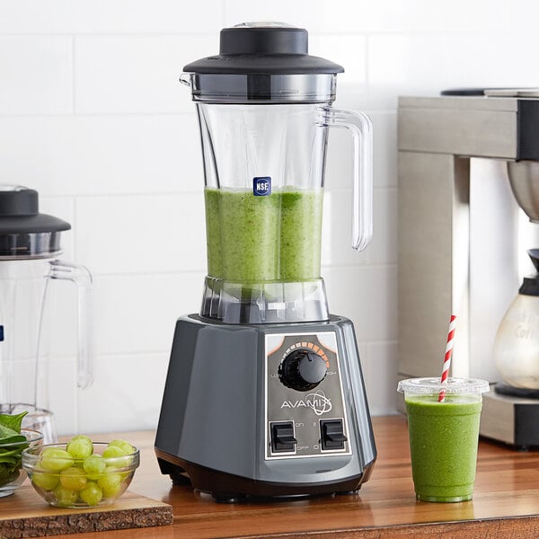 A AvaMix commercial blender with a green smoothie in a plastic cup with a straw.