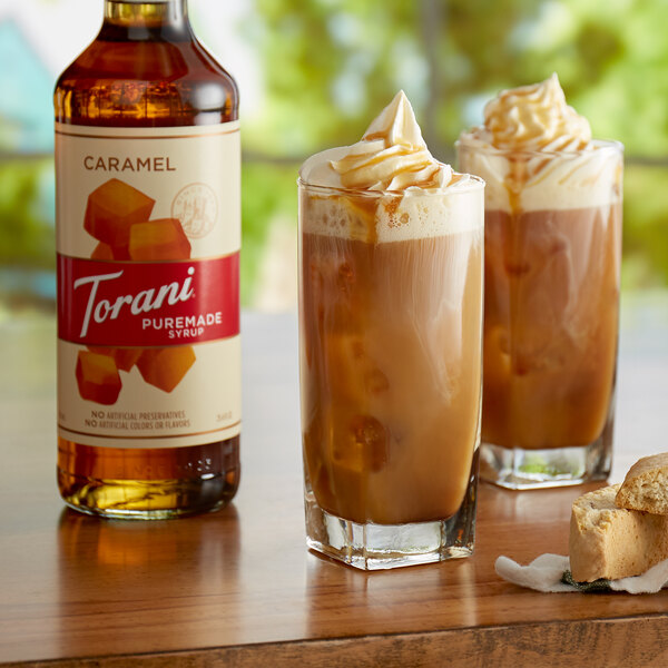 A glass of iced coffee with caramel syrup and a bottle of Torani Puremade Caramel Flavoring Syrup.