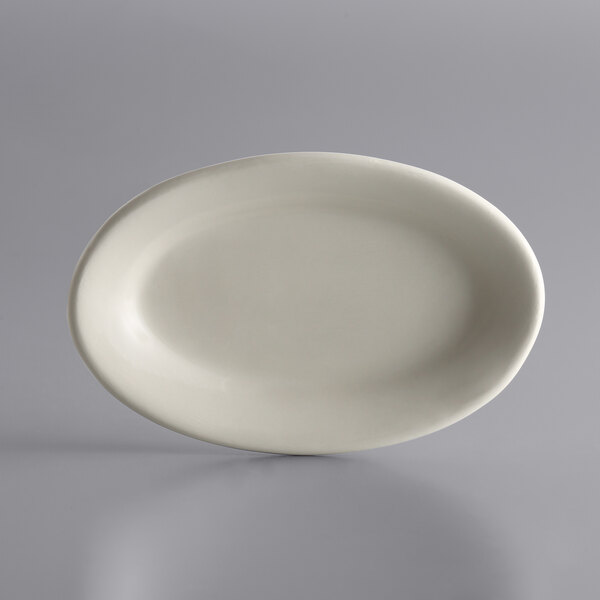 A Libbey Ultima Cream White oval stoneware platter on a gray surface.