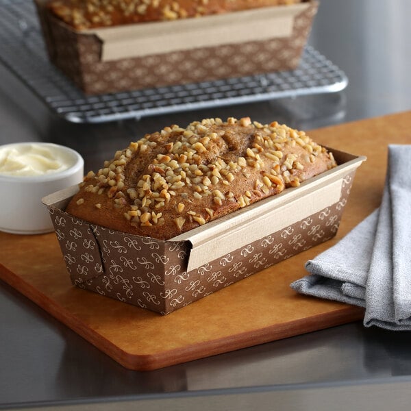 A Solut Bake and Show bread loaf with nuts on top on a cutting board.