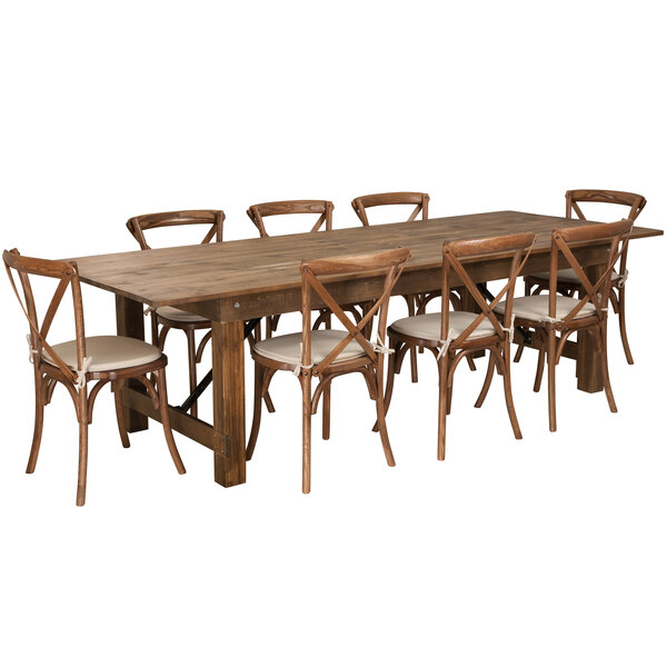 A Flash Furniture rustic wooden farm table with cross back chairs and white cushions.