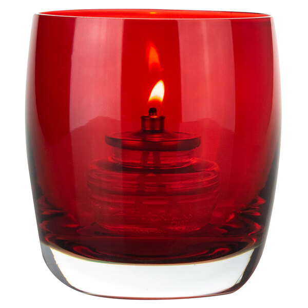 A Sterno red glass votive candle holder with a lit candle inside.