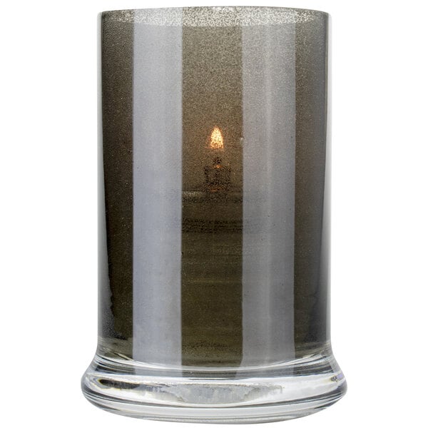 A Sterno glass votive with a lit candle inside.