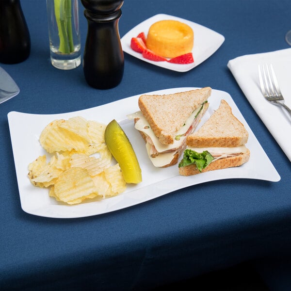 A Fineline white plastic luncheon plate with a sandwich and chips on it.