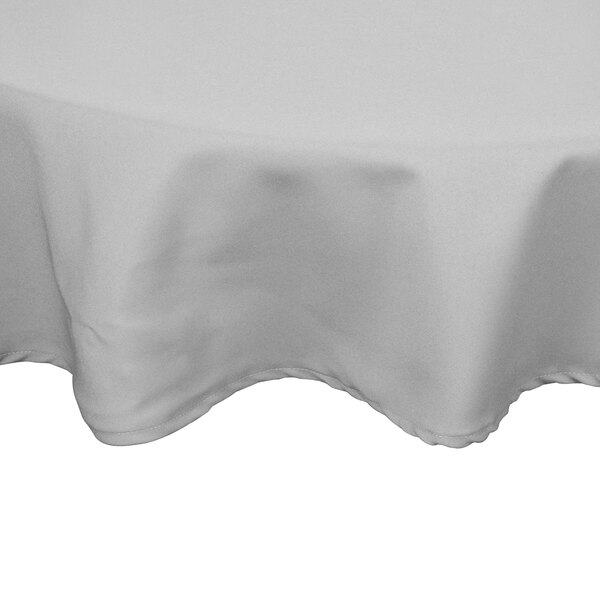 A gray Intedge poly/cotton blend round table cover with hemmed edges on a table.
