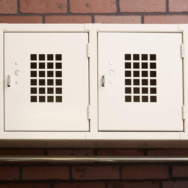 Three Winholt white metal lockers on a brick wall.