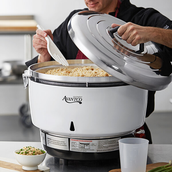 A man using an Avantco rice cooker pot to cook a large batch of rice.