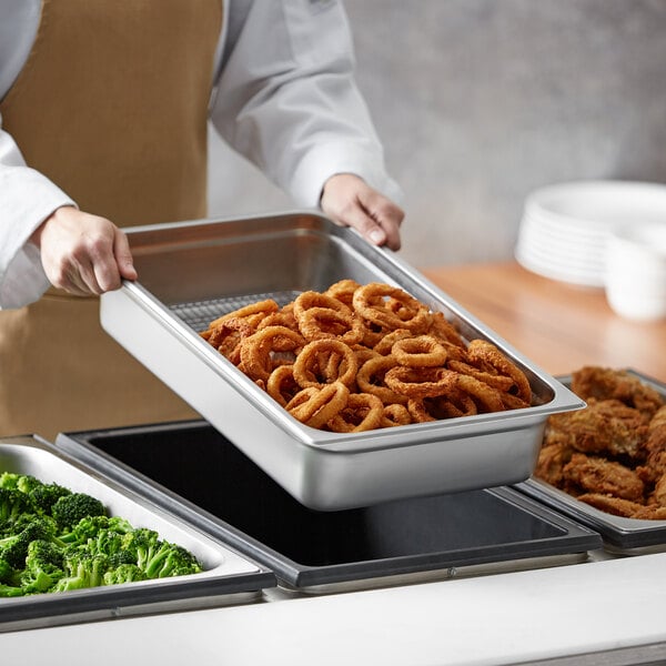 A person holding a Choice stainless steel steam table pan filled with fried onion rings.