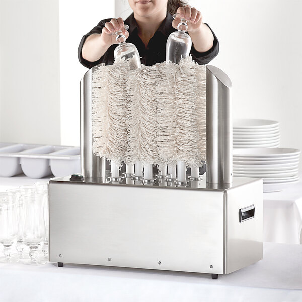 A woman using a Noble Products glass washer machine with a 10-brush set.