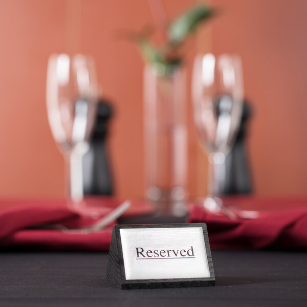 An American Metalcraft black wood "Reserved" sign on a table with wine glasses.